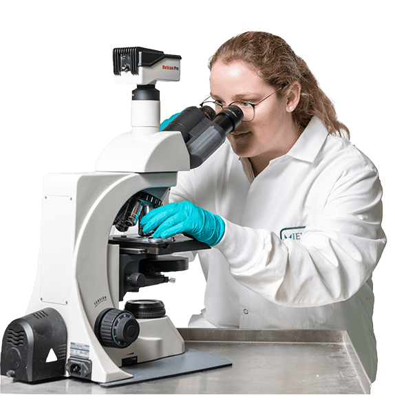 A curious woman wearing a lab coat, peering intently through a microscope. She is engaged in her scientific exploration, surrounded by an array of lab equipment.